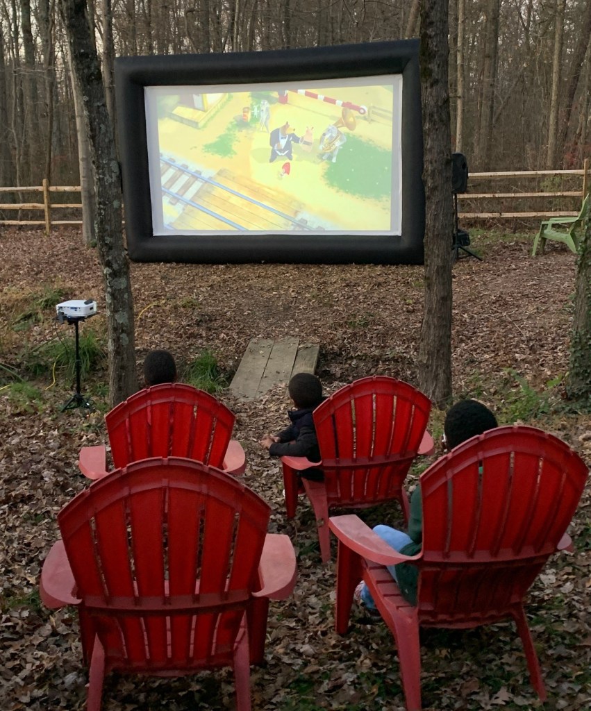 Kids watch a movie on the big screen in our backyard. Equipment furnished by Family Backyard Rentals.