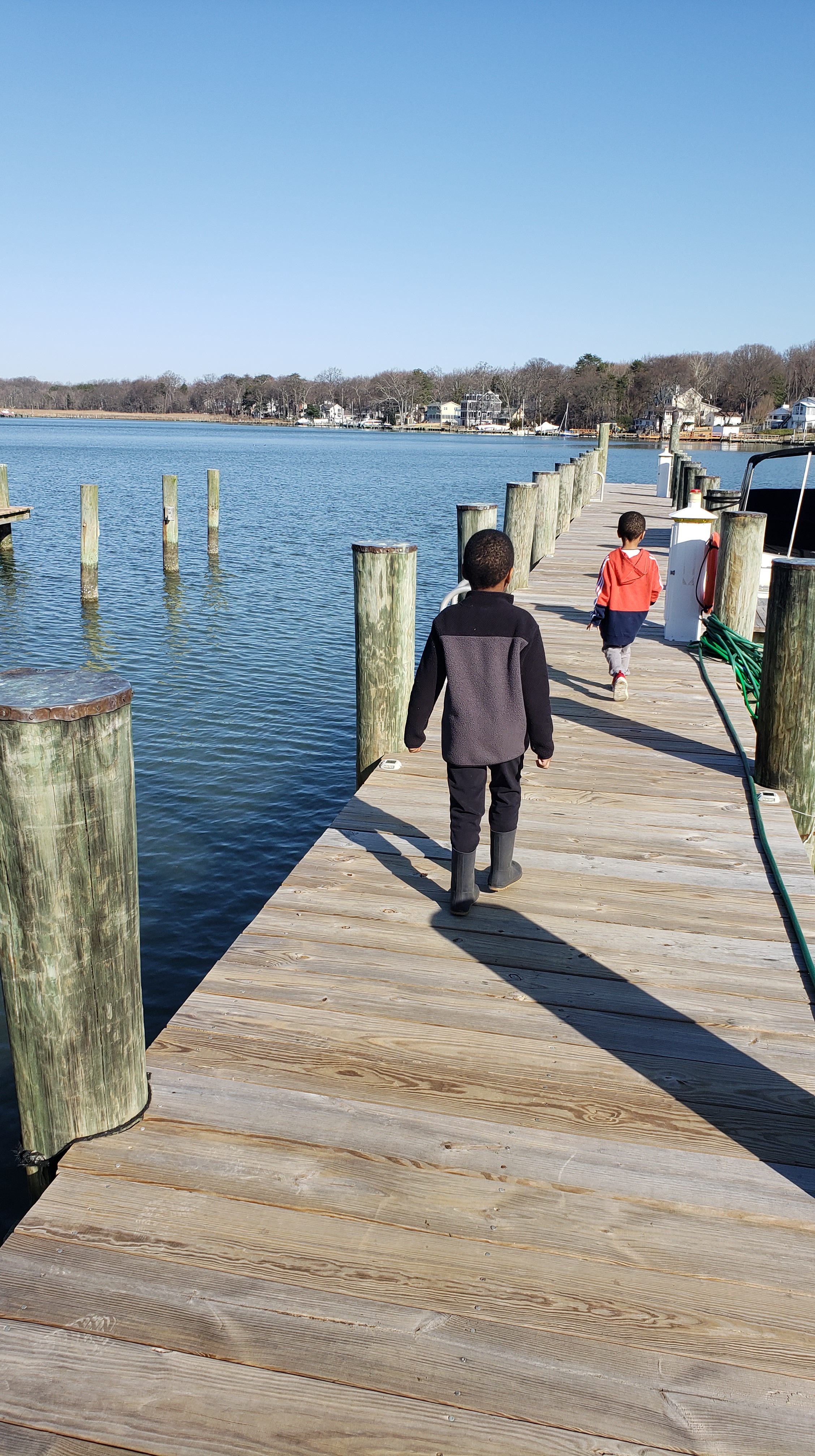 Two kids walking down a pier.